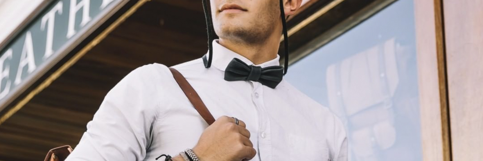 Mann mit Sonnenbrille und Lederkette und Fliege aus Leder