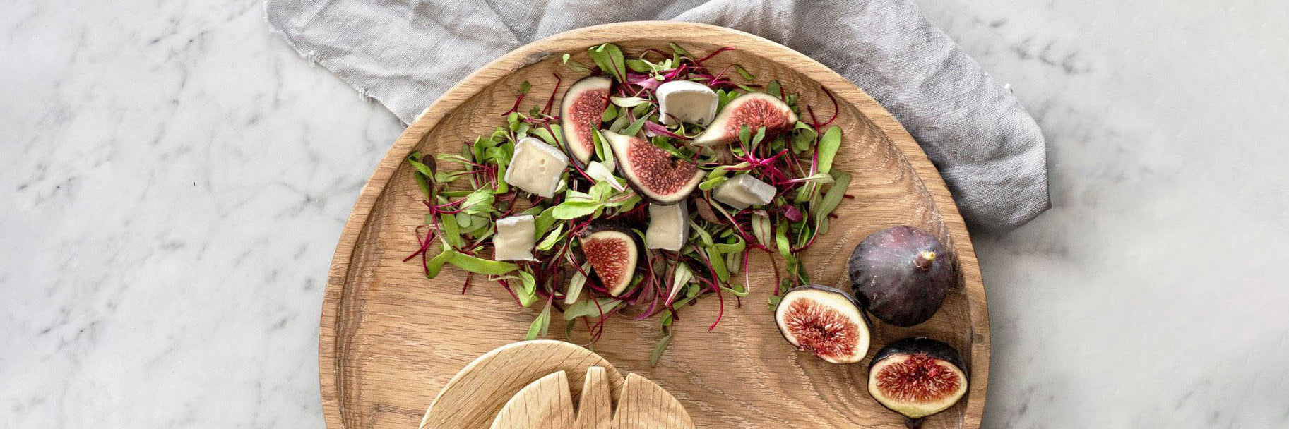 Holzteller mit Feigensalat und Salatbesteck