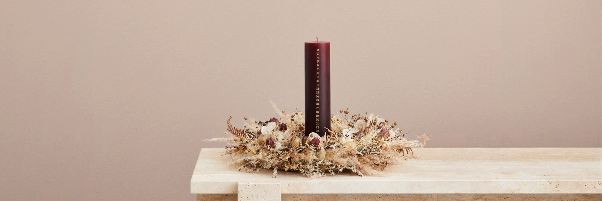 Weihnachtskerze von Ester & Erik mit 24 Zahlen in gold auf einer dunkelroten Stumpenkerze